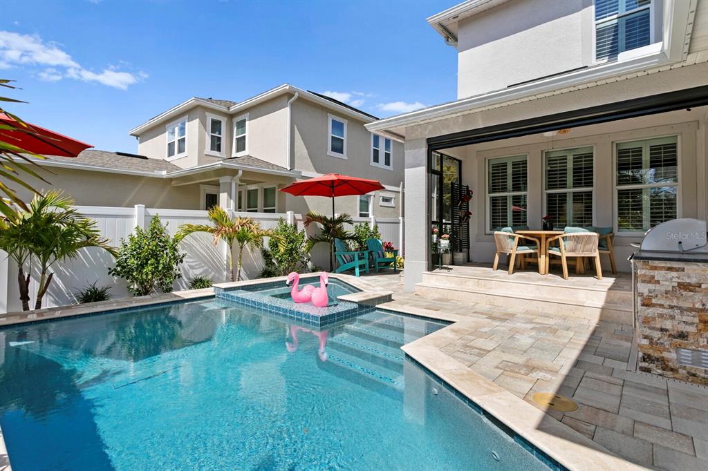 A backyard features a swimming pool with a spa, patio furniture, and a stone grill — 2702 W CASS STREET, TAMPA, FL