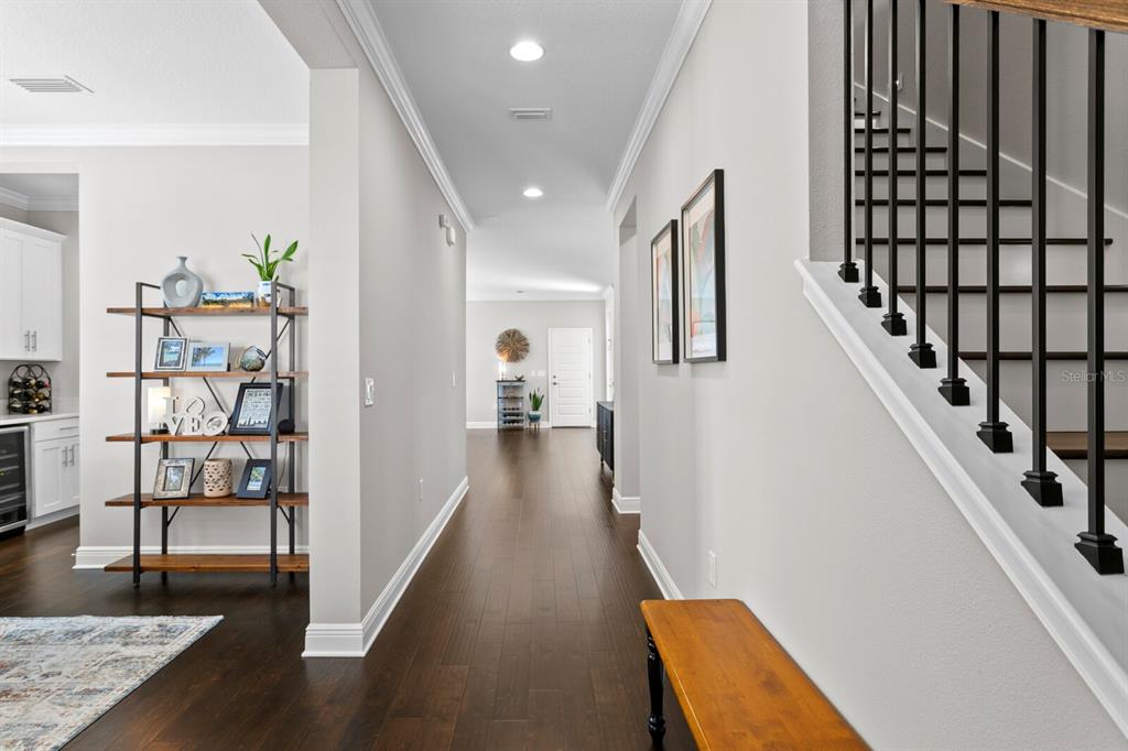 A hallway with dark wood floors, a staircase with black railings, and a decorative bookshelf — 2702 W CASS STREET, TAMPA, FL