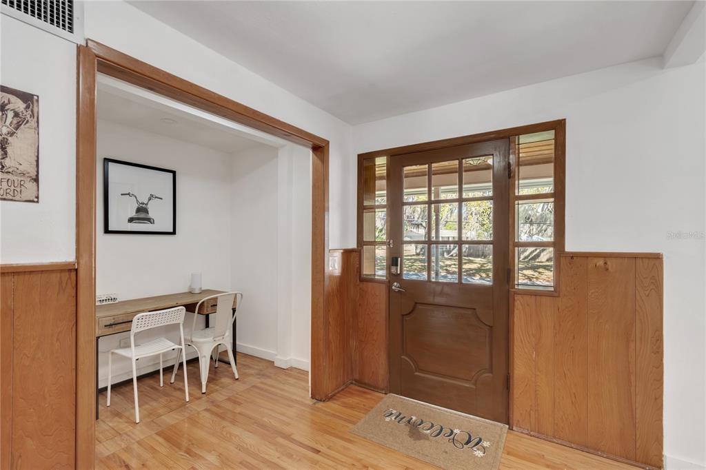 An entryway features wood paneling, a wooden front door with glass panes, and a small desk — 510 SE 19TH STREET, OCALA, FL