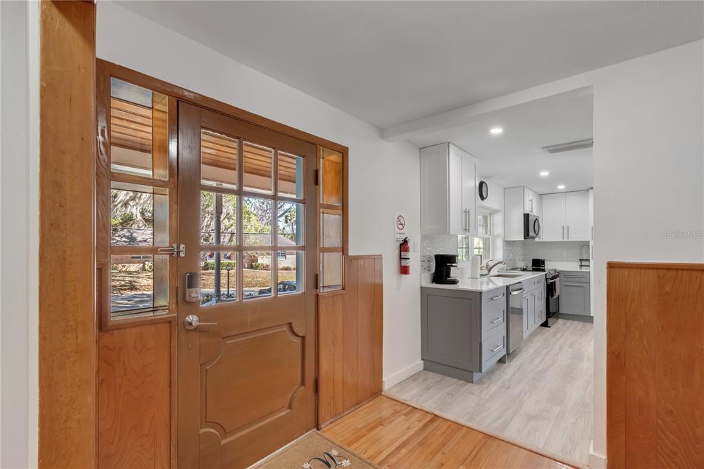 A wood-paneled entryway leads into a modern kitchen with white cabinets and gray lower cupboards — 510 SE 19TH STREET, OCALA, FL