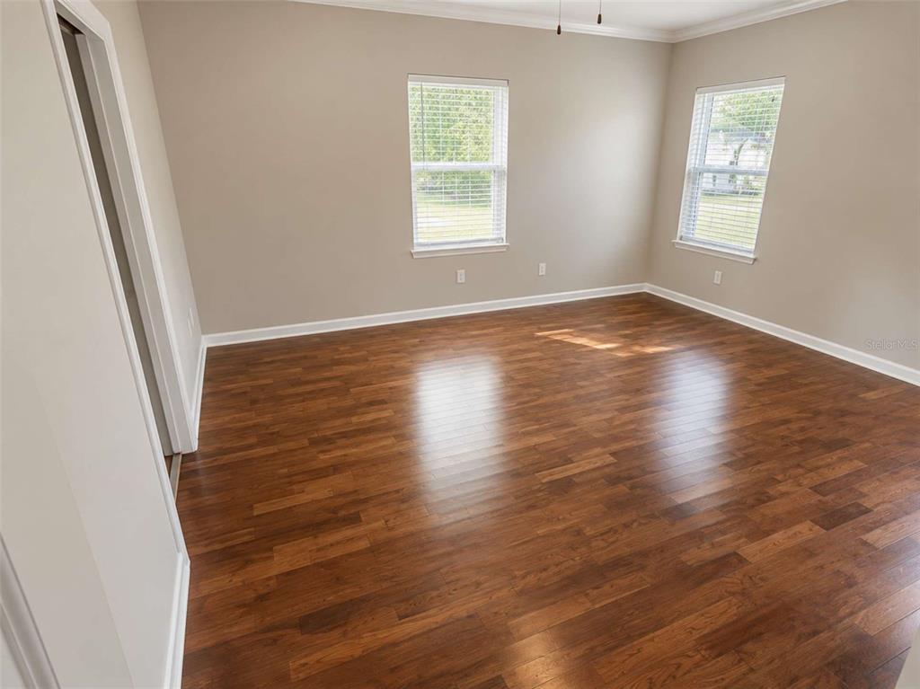 An empty bedroom features light-colored walls, crown molding, and dark wood-look flooring — 3522 W PRICE AVENUE, TAMPA, FL