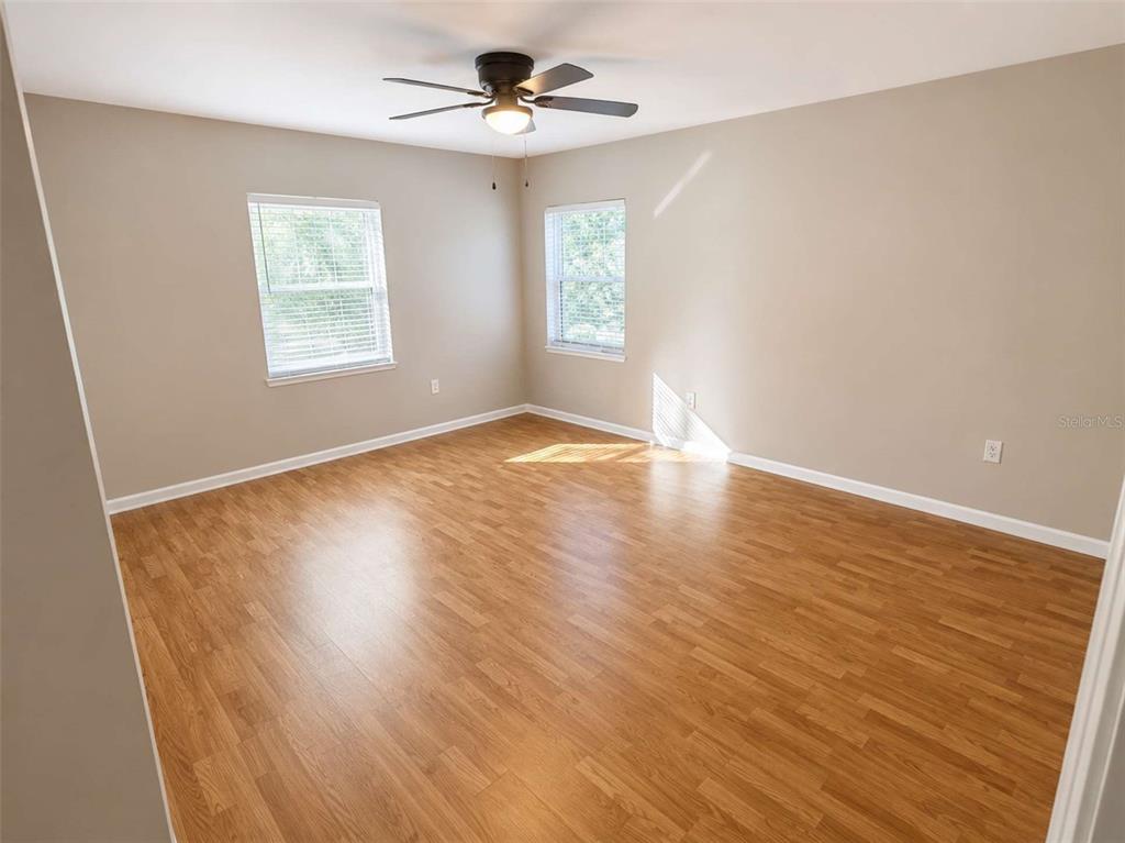 An empty bedroom features light-colored walls, wood-look flooring, two windows, and a ceiling fan — 3522 W PRICE AVENUE, TAMPA, FL