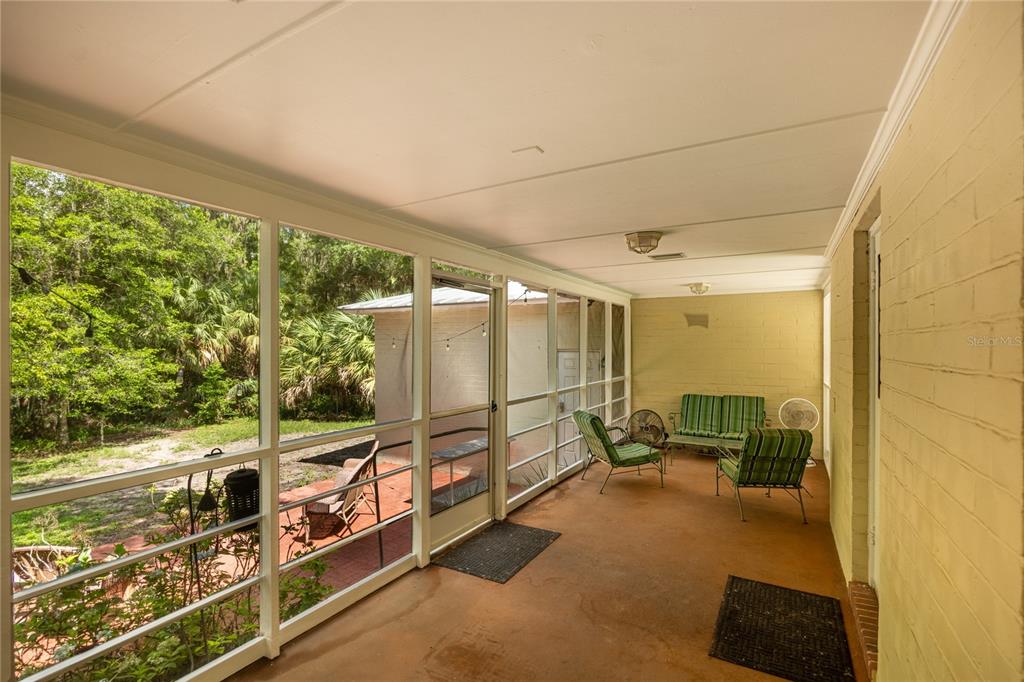 A screened-in porch with a concrete floor, yellow brick walls, and outdoor furniture — 434 NW 25TH STREET, GAINESVILLE, FL