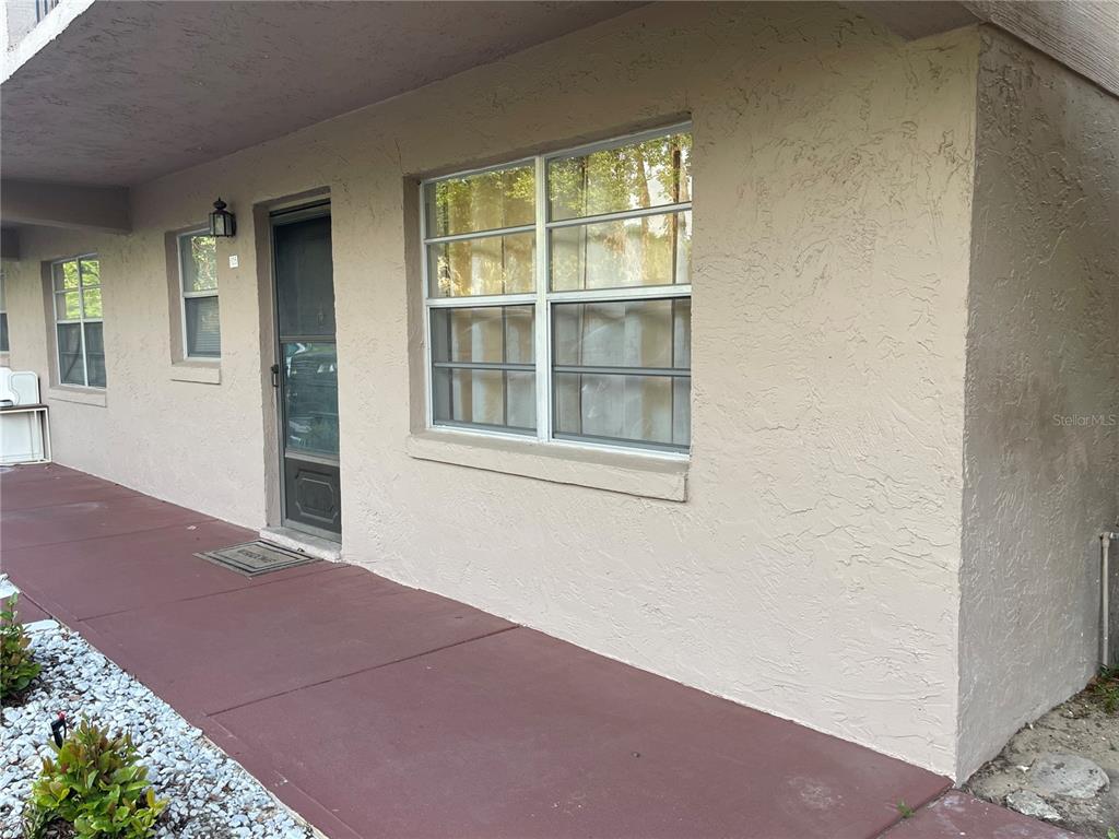 A beige stucco exterior wall features a front door and a large window — 150 EL DORADO UNIT 105, WINTER HAVEN, FL