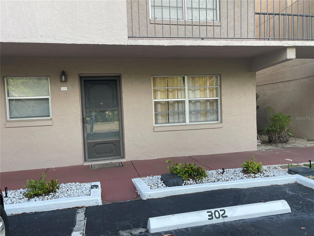 The exterior view shows a ground-level apartment entrance with a screen door and windows — 150 EL DORADO UNIT 105, WINTER HAVEN, FL