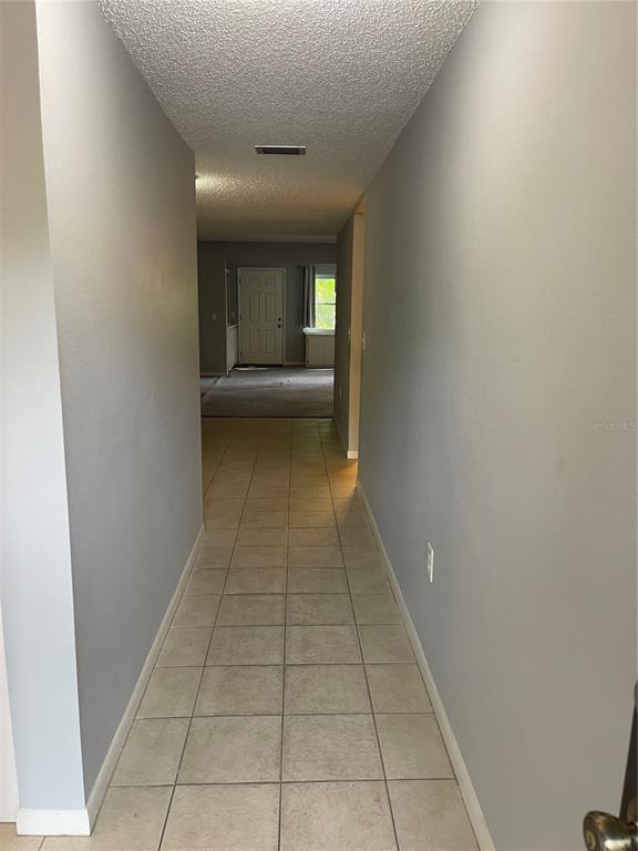 A tiled hallway leads from the foreground toward a living area with a front door — 150 EL DORADO UNIT 105, WINTER HAVEN, FL