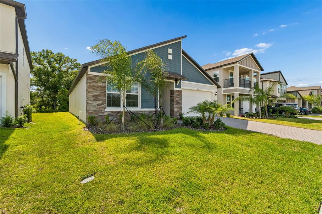 A single-story house with blue siding, stone accents, and a front-facing garage — 18542 SERENE LAKE LOOP, LUTZ, FL