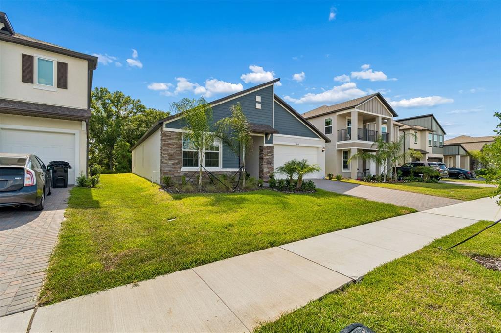 A single-story house with blue siding, stone accents, and a two-car garage — 18542 SERENE LAKE LOOP, LUTZ, FL