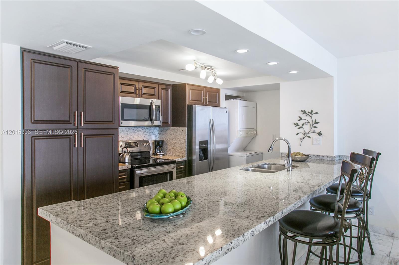 A kitchen features dark wood cabinets, granite countertops, stainless steel appliances, and a breakfast bar — 1717 N Bayshore Dr # 3751, Miami FL 33132, MIAMI, FL