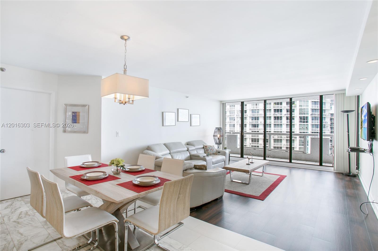 A dining area and living room feature light wood furniture, white seating, and floor-to-ceiling windows — 1717 N Bayshore Dr # 3751, Miami FL 33132, MIAMI, FL