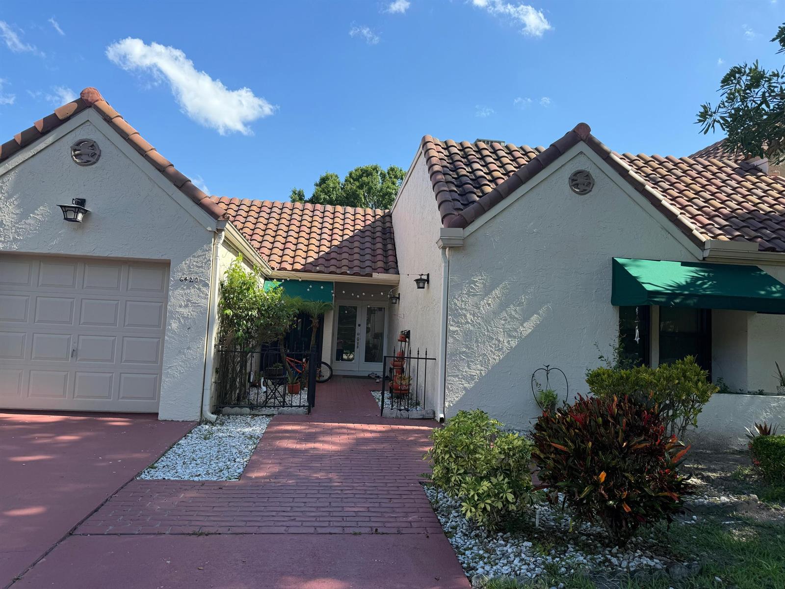 A single-story house with a tiled roof, brick walkway, and a garage under a blue sky — 6420 Via Tierra, Boca Raton FL 33433, BOCA RATON, FL