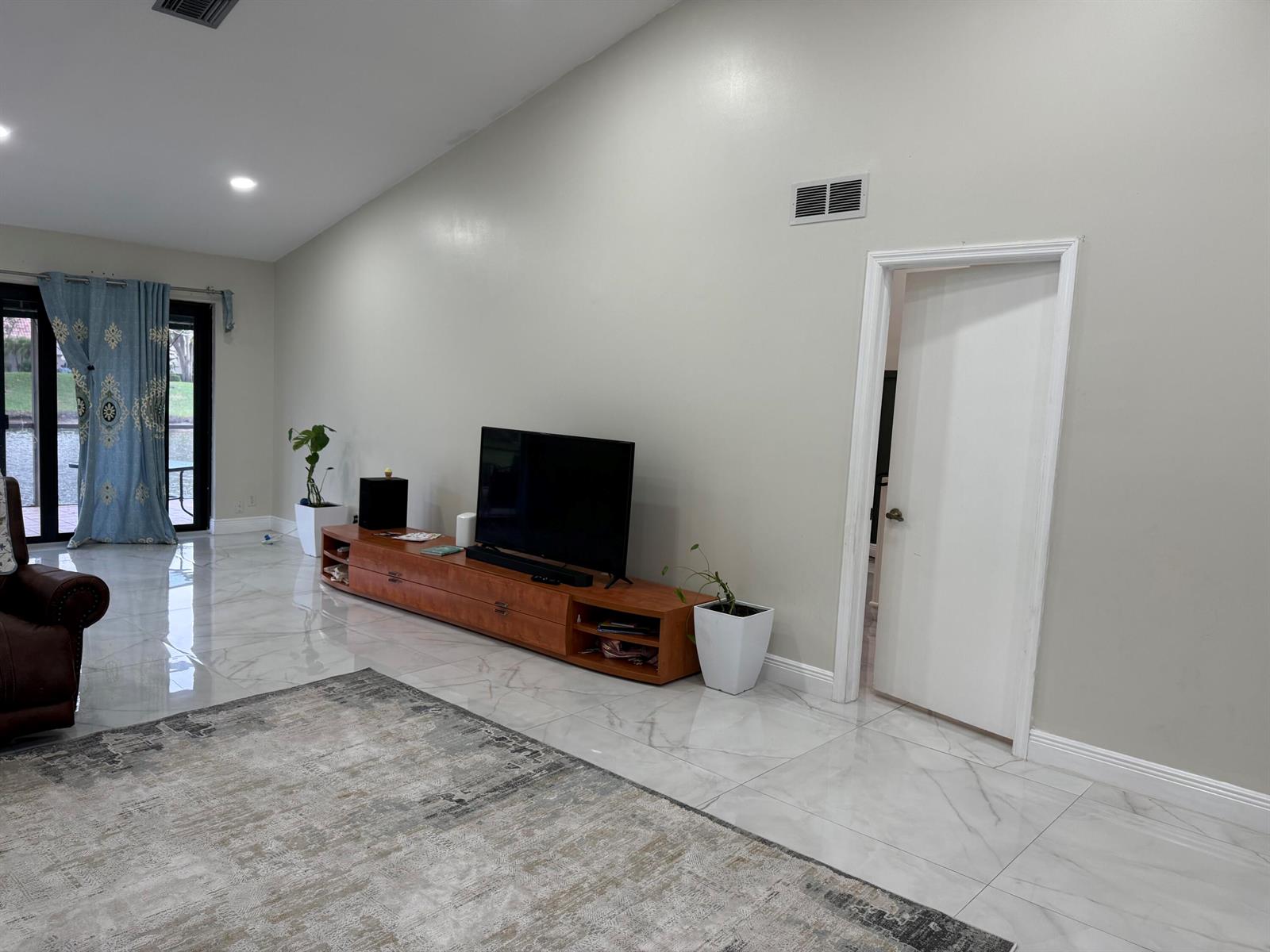 A living room features a large television on a wooden console, tile floors, and curtains — 6420 Via Tierra, Boca Raton FL 33433, BOCA RATON, FL
