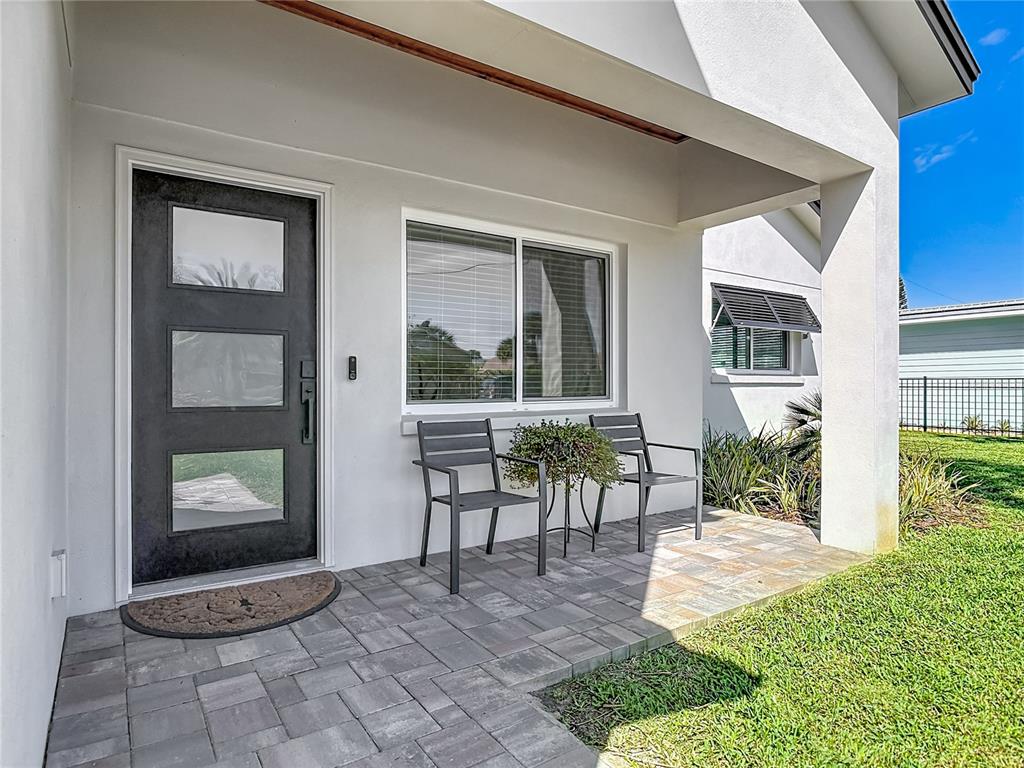 A modern front entryway features a dark door with glass panels and a paved porch — 214 CONDICT DRIVE, NEW SMYRNA BEACH, FL