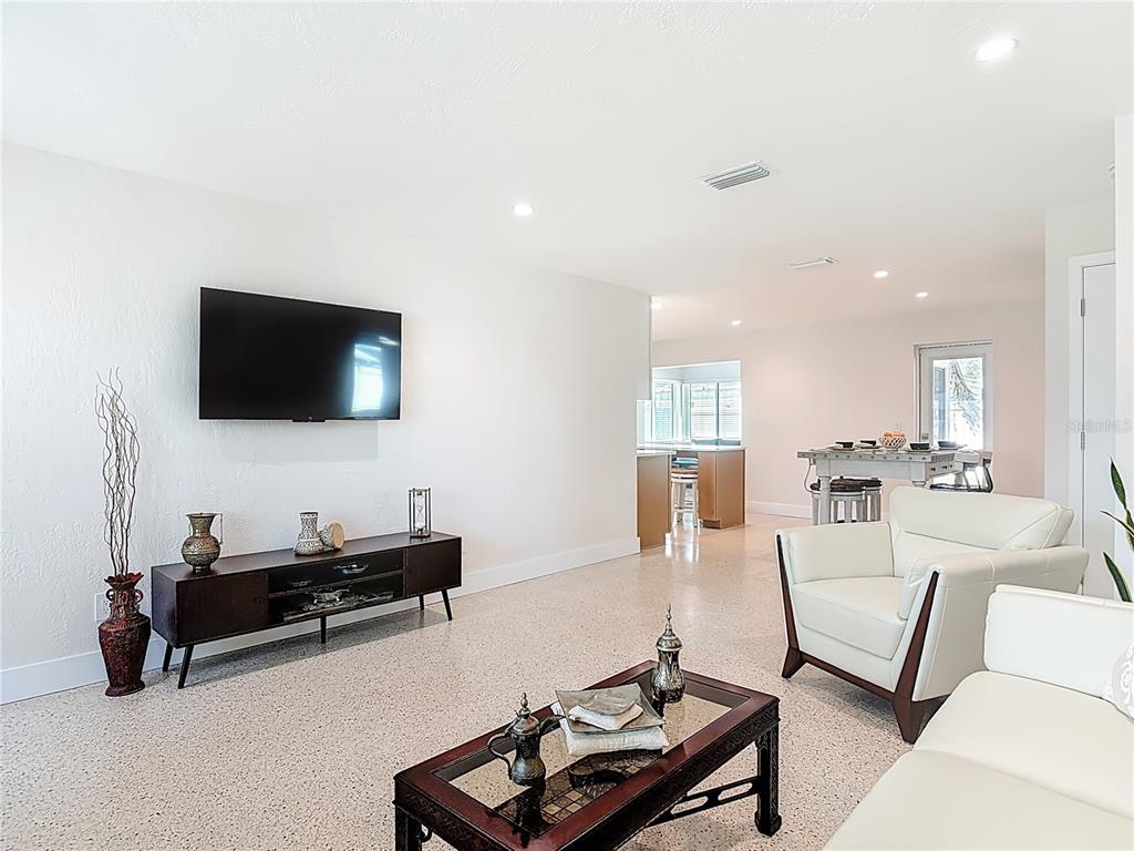 A living room features a wall-mounted television, dark wood furniture, and white leather seating — 214 CONDICT DRIVE, NEW SMYRNA BEACH, FL