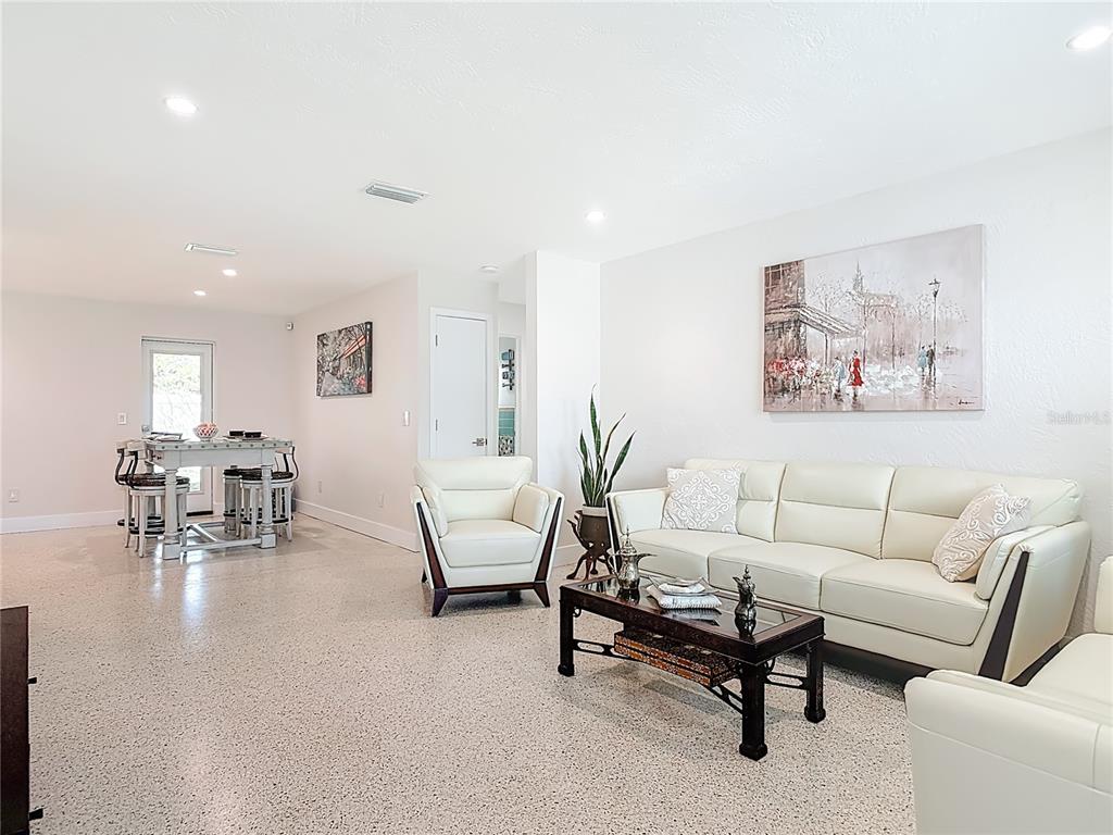 A living room with white leather furniture, a coffee table, and a dining area nearby — 214 CONDICT DRIVE, NEW SMYRNA BEACH, FL