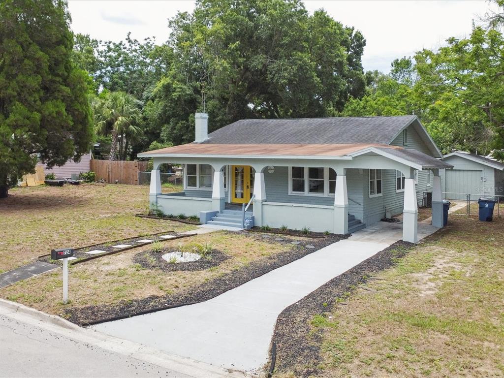 A light green bungalow with a yellow front door, a covered porch, and a driveway — 724 EUCLID AVENUE, LAKE WALES, FL