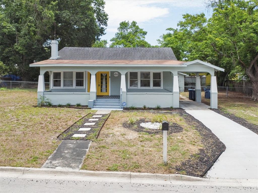 A light gray bungalow with a yellow front door, a front porch, and a carport — 724 EUCLID AVENUE, LAKE WALES, FL