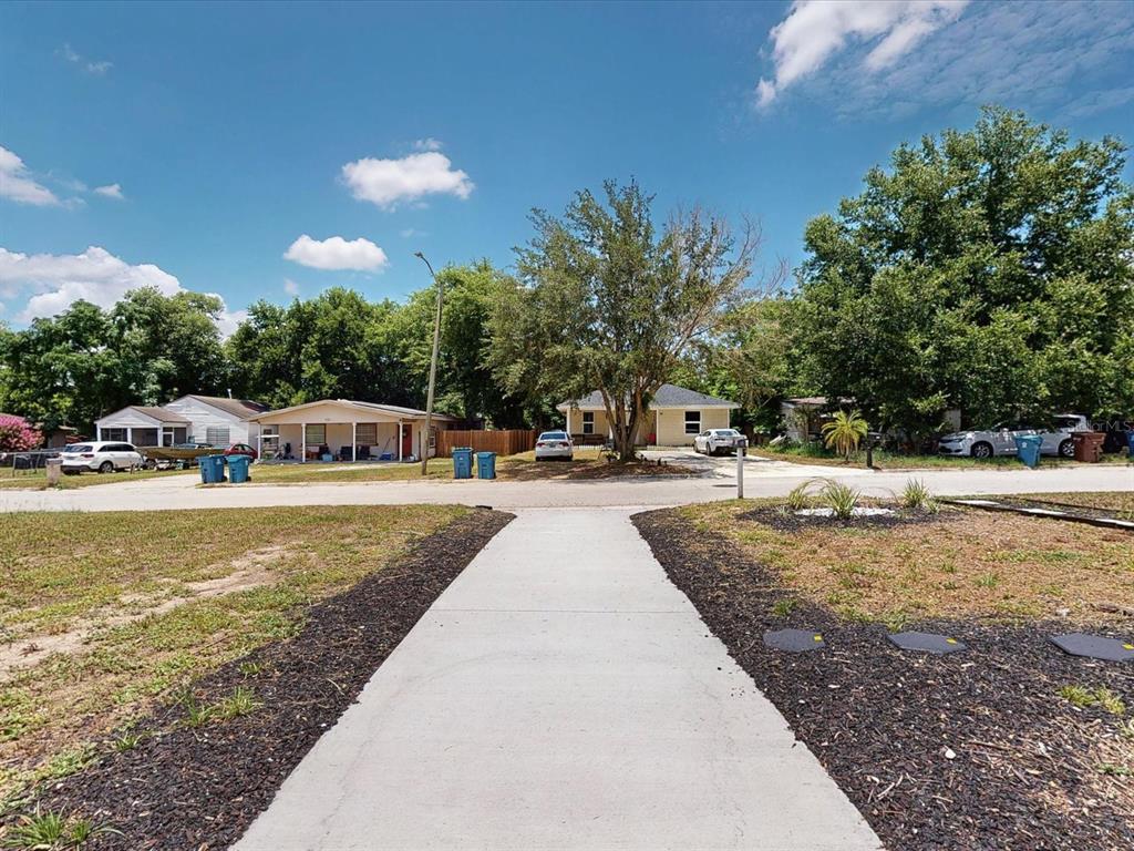 A concrete walkway leads toward a residential street with several single-story houses and parked cars — 724 EUCLID AVENUE, LAKE WALES, FL