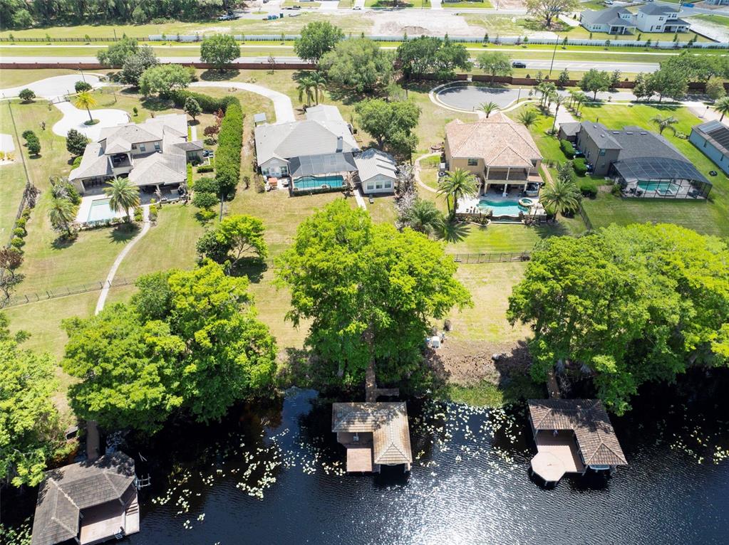 An aerial view shows four waterfront houses with swimming pools and private boat docks — 3308 LUKAS COVE, ORLANDO, FL