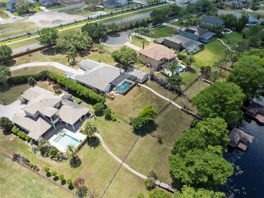 An aerial view shows several houses with swimming pools and large yards bordering a lake — 3308 LUKAS COVE, ORLANDO, FL