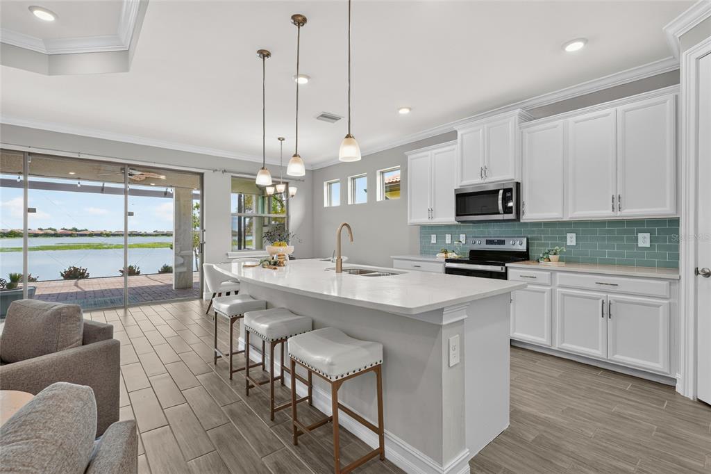 A kitchen with white cabinets, a quartz island, and a view of a lake outside — 696 RAVELLO BOULEVARD, NOKOMIS, FL