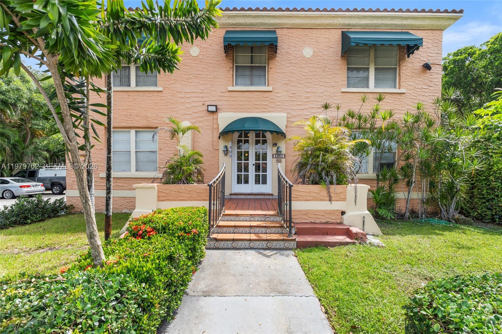 A two-story peach-colored building features a central arched entryway with a green awning — 3409 S Le Jeune Rd, Coral Gables FL 33134, CORAL GABLES, FL