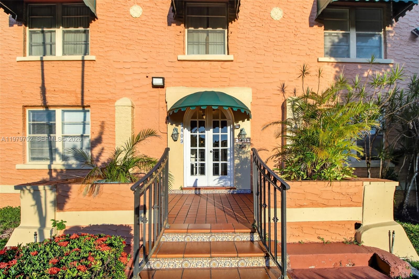 The exterior of a peach-colored building features a central entrance with a green awning — 3409 S Le Jeune Rd, Coral Gables FL 33134, CORAL GABLES, FL