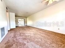 An empty room features brown carpeting, white walls, and a sliding glass door — 24862 US HIGHWAY 19 N UNIT 3202, CLEARWATER, FL