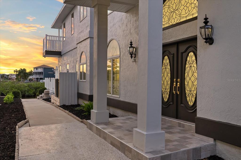 A white house exterior features a covered entryway with columns and double doors with glass — 6121 BAYSIDE DRIVE, NEW PORT RICHEY, FL