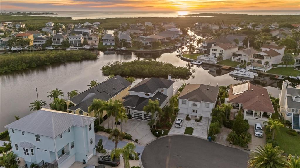 An aerial view shows waterfront houses with docks and boats along a canal at sunset — 6121 BAYSIDE DRIVE, NEW PORT RICHEY, FL