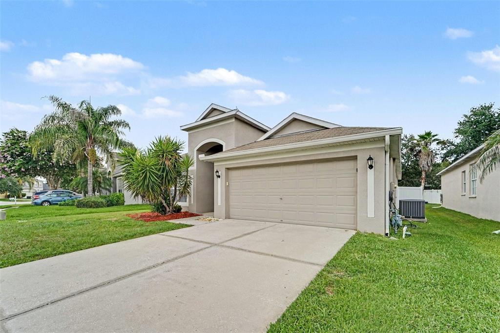 A beige single-story house with a two-car garage and a concrete driveway — 4906 PENNECOTT WAY, WESLEY CHAPEL, FL