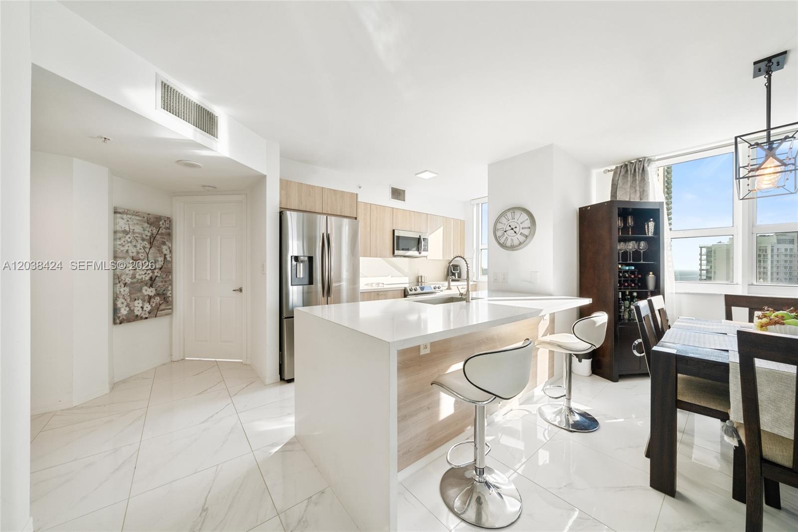 A modern kitchen features white marble floors, a central island with barstools, and stainless appliances — 1155 Brickell Bay Dr # 2501, Miami FL 33131, MIAMI, FL