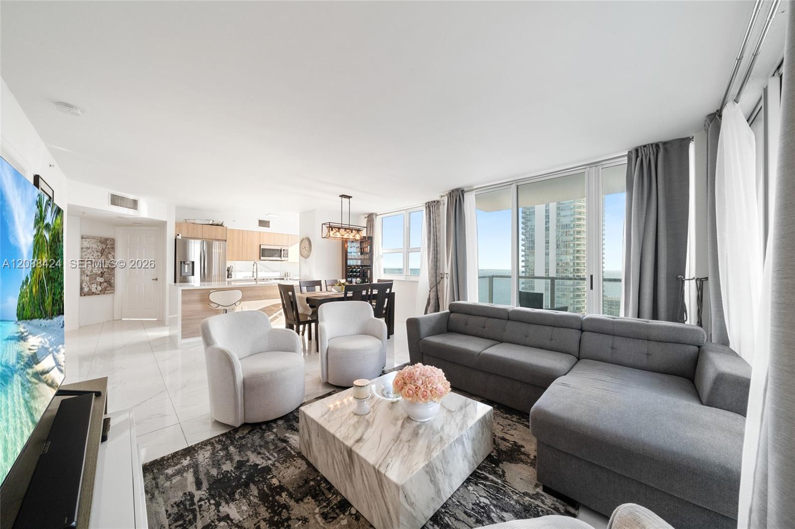 A living room with a grey sectional, marble coffee table, and an open-concept kitchen — 1155 Brickell Bay Dr # 2501, Miami FL 33131, MIAMI, FL