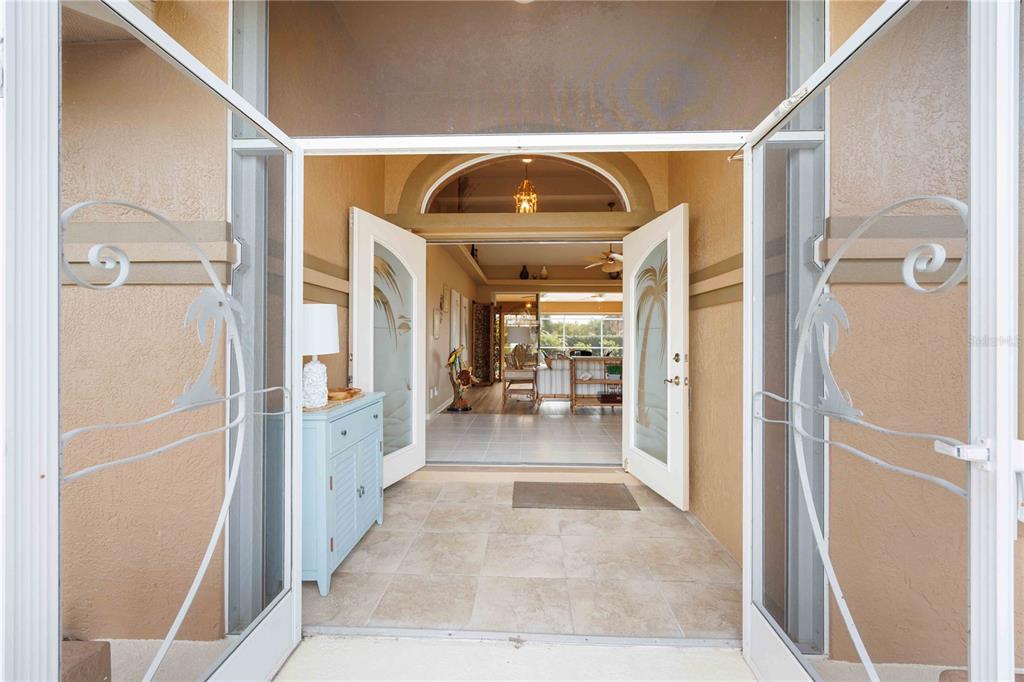 A view through an open double door into a tiled entryway and living area beyond — 55 CLUBHOUSE ROAD, ROTONDA WEST, FL