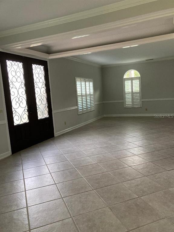 An empty room features tile flooring, light gray walls, and dark double doors with ironwork — 224 HUNTRIDGE WAY, WINTER SPRINGS, FL