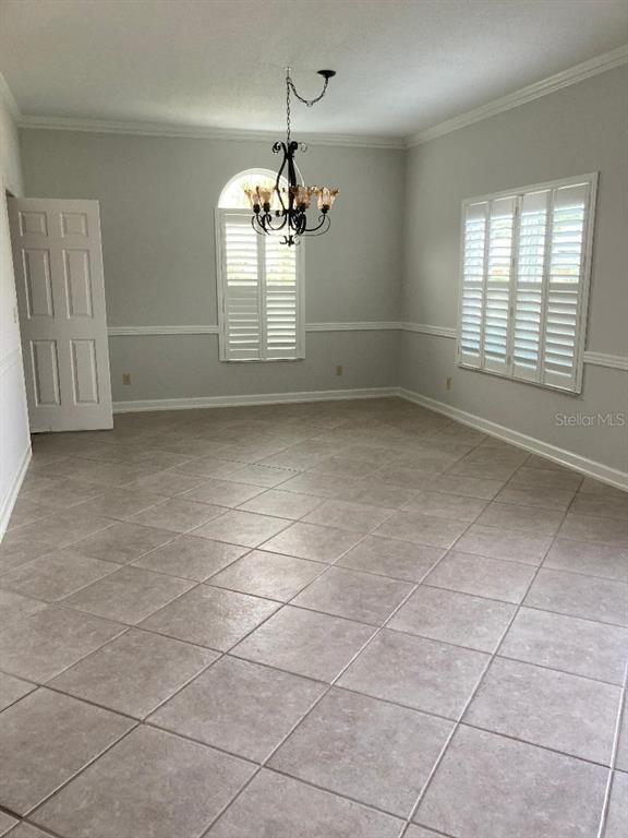 An empty dining room features light gray walls, tile flooring, a chandelier, and plantation shutters — 224 HUNTRIDGE WAY, WINTER SPRINGS, FL