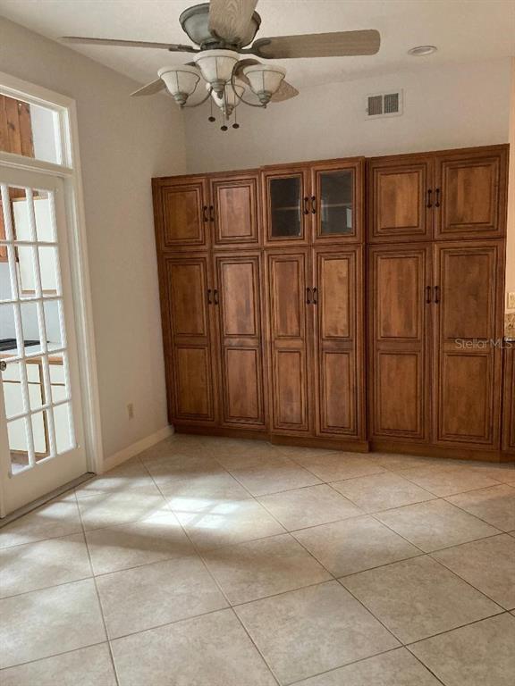 A room with tile flooring, a ceiling fan, and a large wall of wooden cabinetry — 224 HUNTRIDGE WAY, WINTER SPRINGS, FL