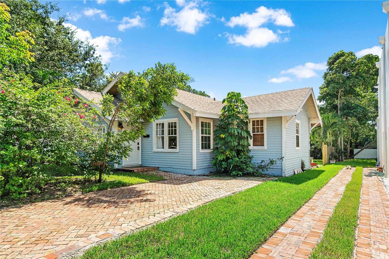 A light blue, single-story house with a brick driveway and lush green landscaping — 728 Newark St, West Palm Beach FL 33401, WEST PALM BEACH, FL