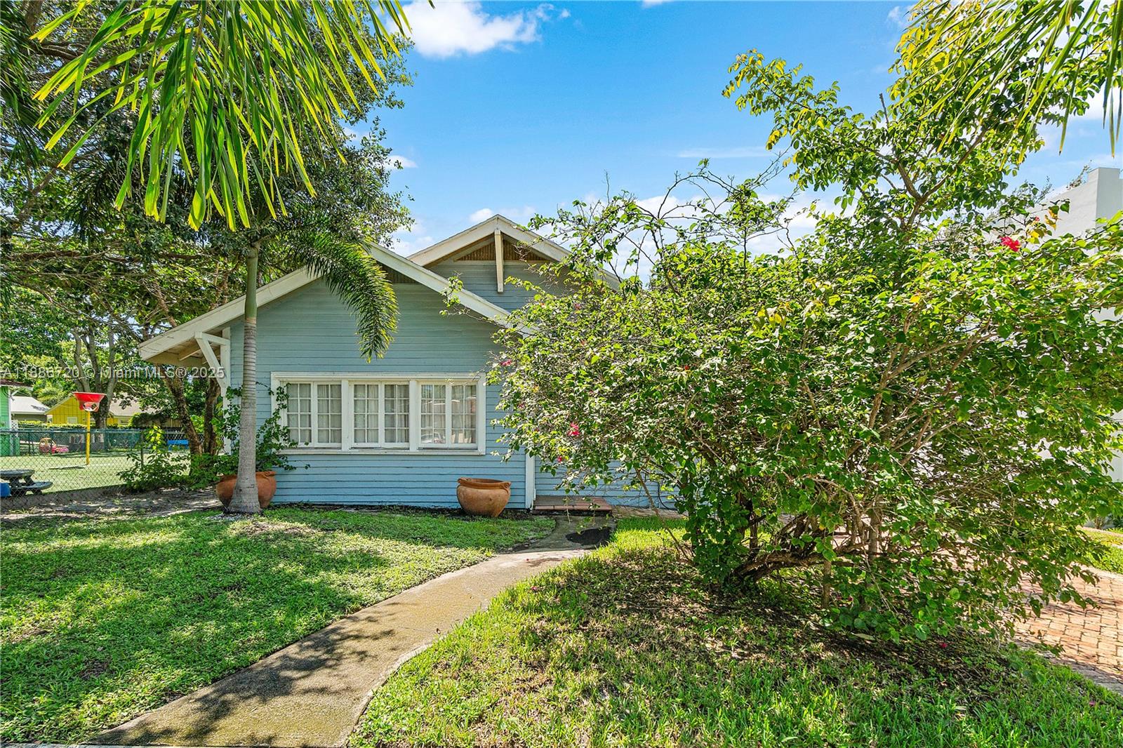 A light blue house with a gabled roof sits behind a large green bush — 728 Newark St, West Palm Beach FL 33401, WEST PALM BEACH, FL