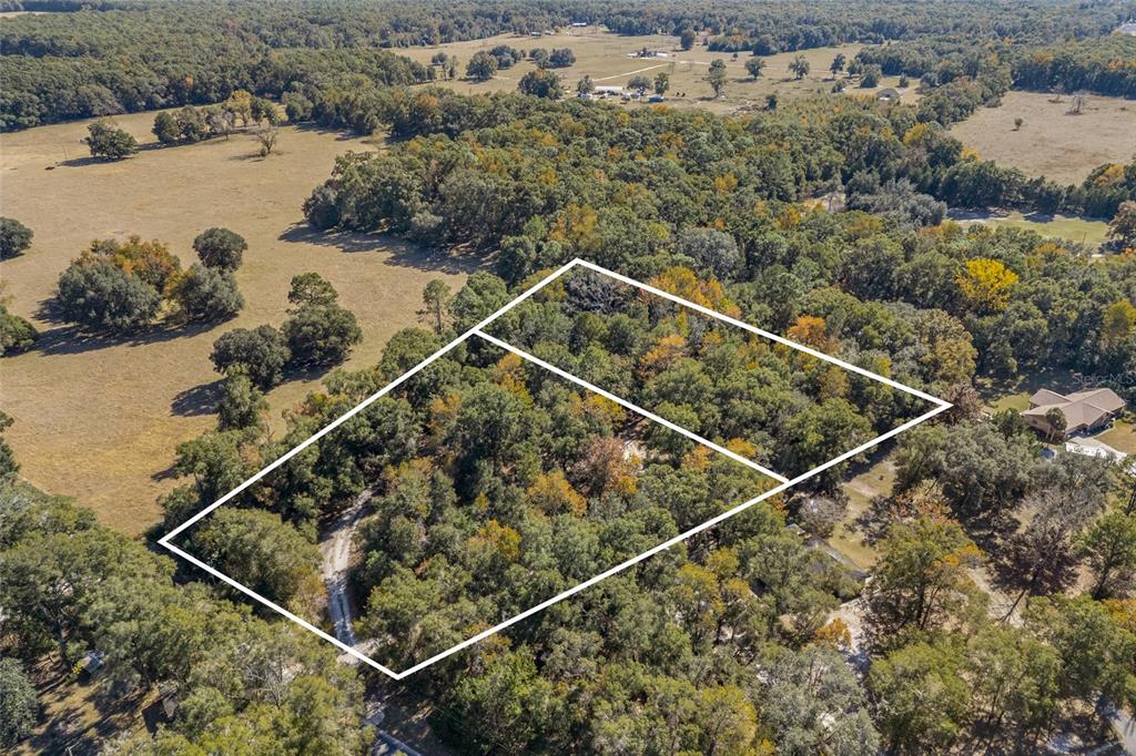An aerial view shows two adjacent wooded lots outlined in white within a rural landscape — 22647 NW 210TH AVENUE, HIGH SPRINGS, FL