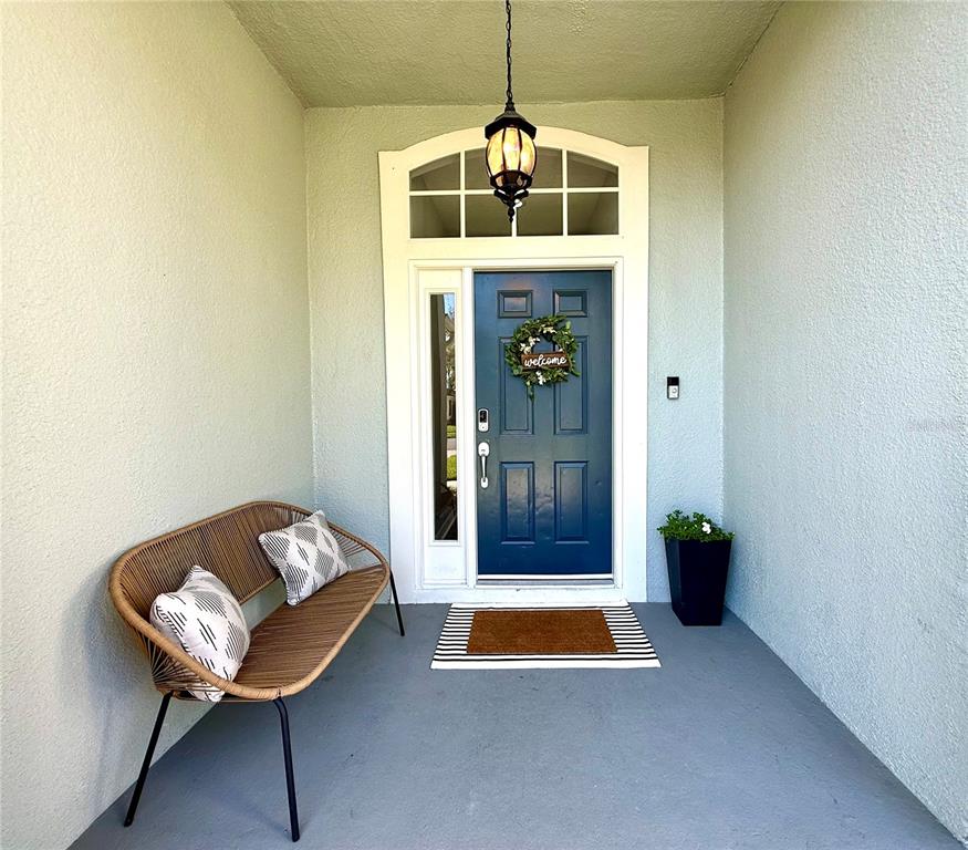A covered front porch features a blue door, a wicker bench, and a hanging lantern — 2532 VENTURA CIRCLE, WEST MELBOURNE, FL