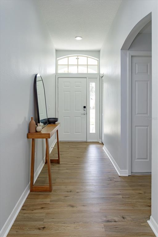 A bright entryway features light wood-look flooring, a console table with a mirror, and a door — 2532 VENTURA CIRCLE, WEST MELBOURNE, FL