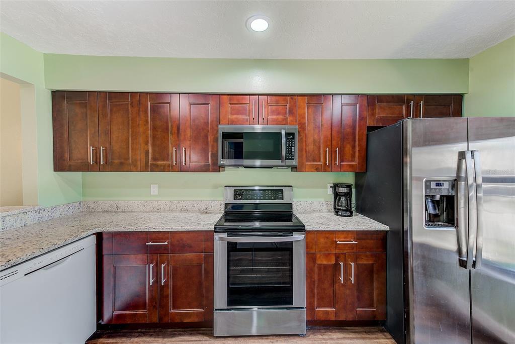 A kitchen features dark wood cabinets, granite countertops, and stainless steel appliances — 6040 27TH STREET W, BRADENTON, FL
