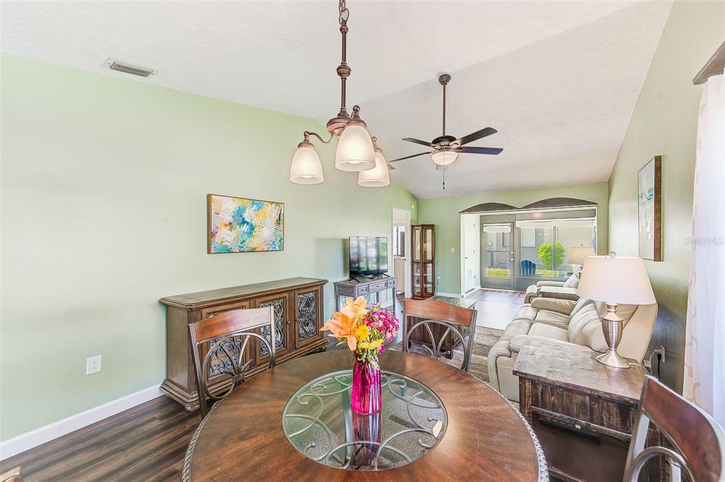 A dining area with a round table and chandelier opens into a living room space — 6040 27TH STREET W, BRADENTON, FL