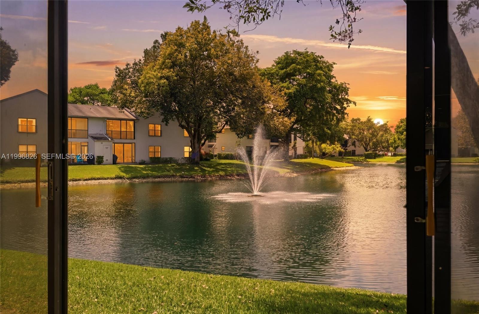 A view of a lake with a fountain and apartment buildings at sunset — 4790 NW 22nd St, Coconut Creek FL 33063, COCONUT CREEK, FL