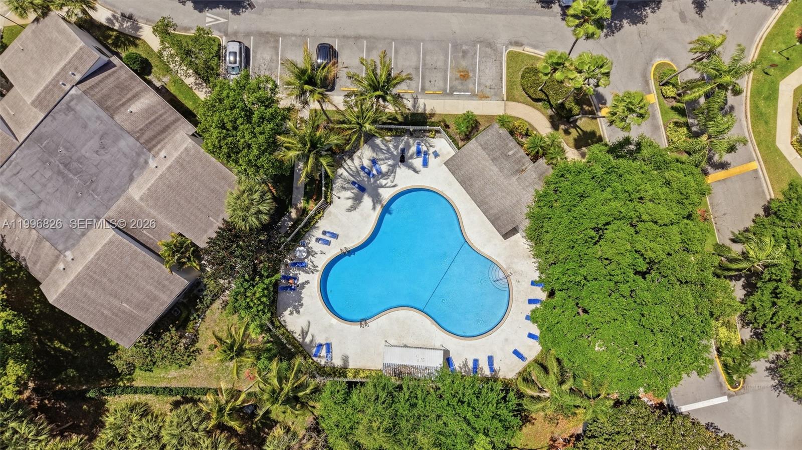 An aerial view shows a clover-shaped swimming pool surrounded by a patio and lush trees — 4790 NW 22nd St, Coconut Creek FL 33063, COCONUT CREEK, FL