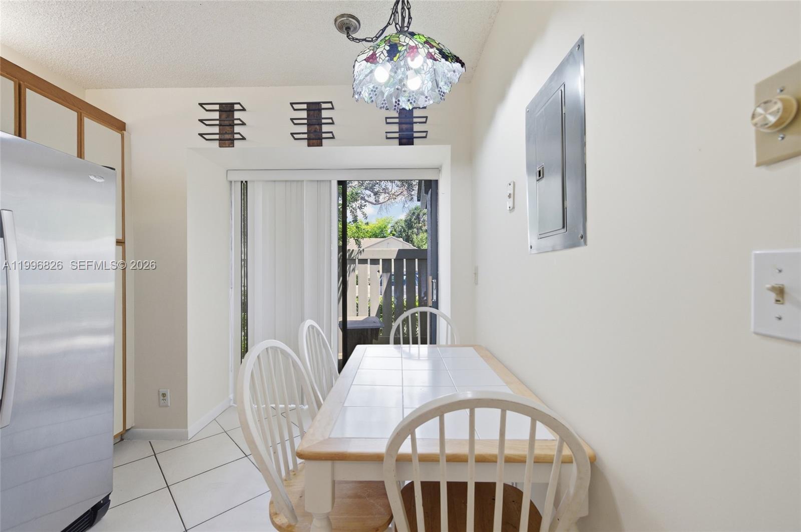 A dining area features a tiled table, white chairs, a stained-glass light, and sliding doors — 4790 NW 22nd St, Coconut Creek FL 33063, COCONUT CREEK, FL