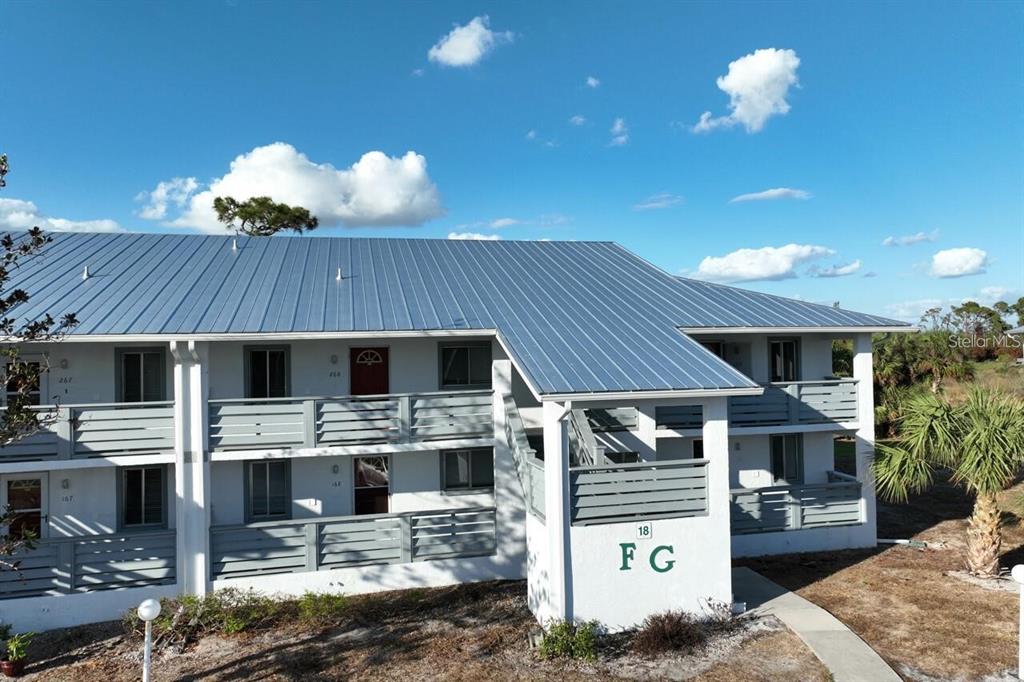 An exterior view of a two-story apartment building with a metal roof and balconies — 6800 PLACIDA ROAD UNIT 168, ENGLEWOOD, FL