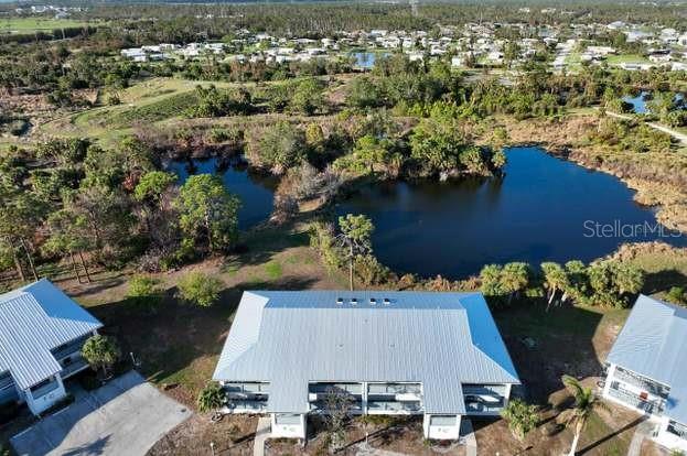 An aerial view shows a multi-story building with a metal roof overlooking a pond — 6800 PLACIDA ROAD UNIT 168, ENGLEWOOD, FL