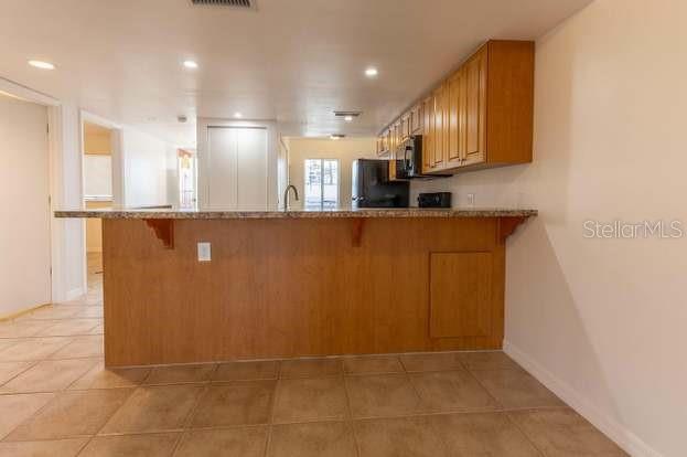 A kitchen features a wooden breakfast bar, light tile flooring, and light wood cabinets — 6800 PLACIDA ROAD UNIT 168, ENGLEWOOD, FL